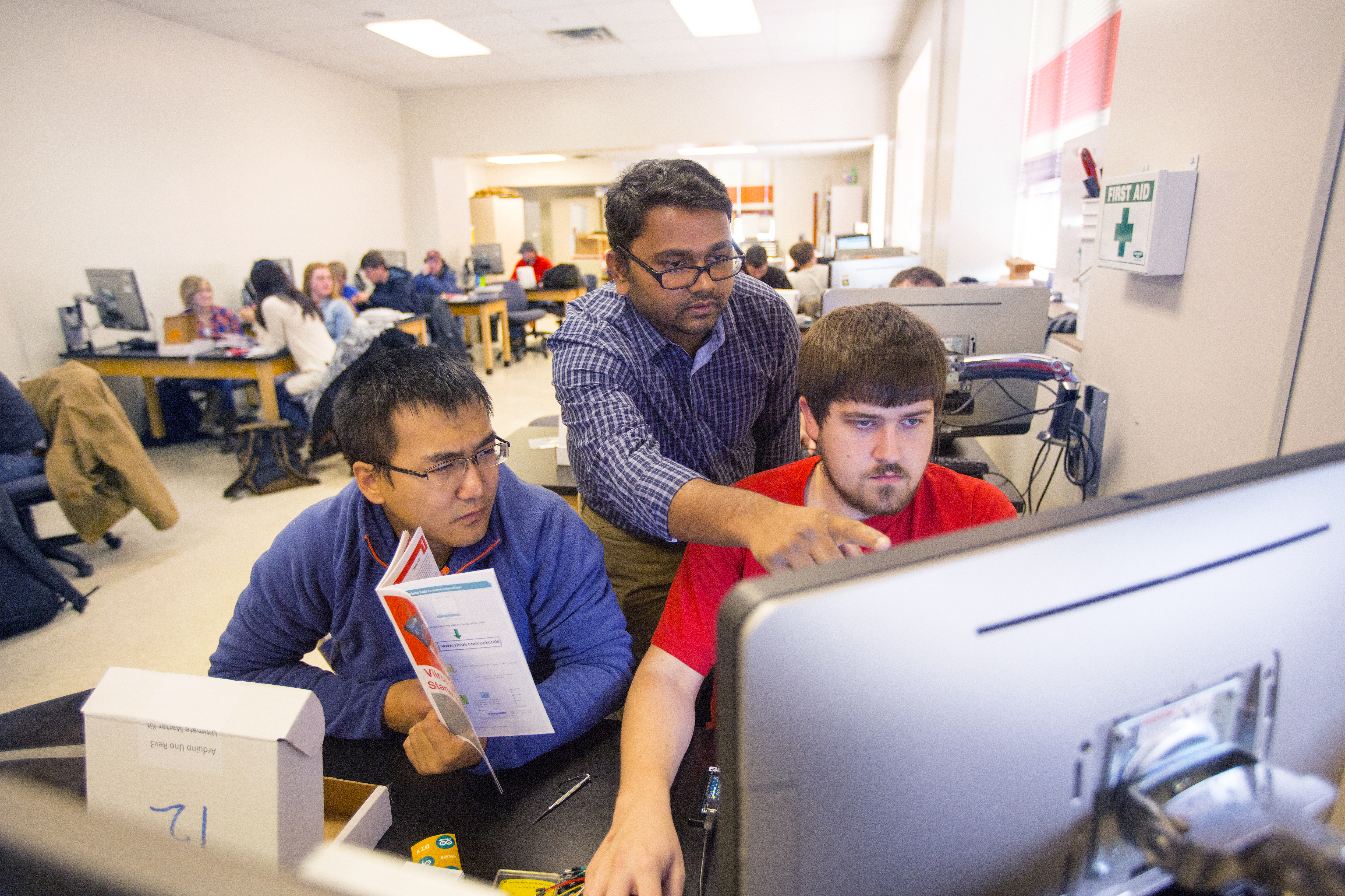 Nebraska researcher Santosh Pitla (center) assists students with a sensor-building project. Pitla is leading a new research project that will update techniques used to test tractors.