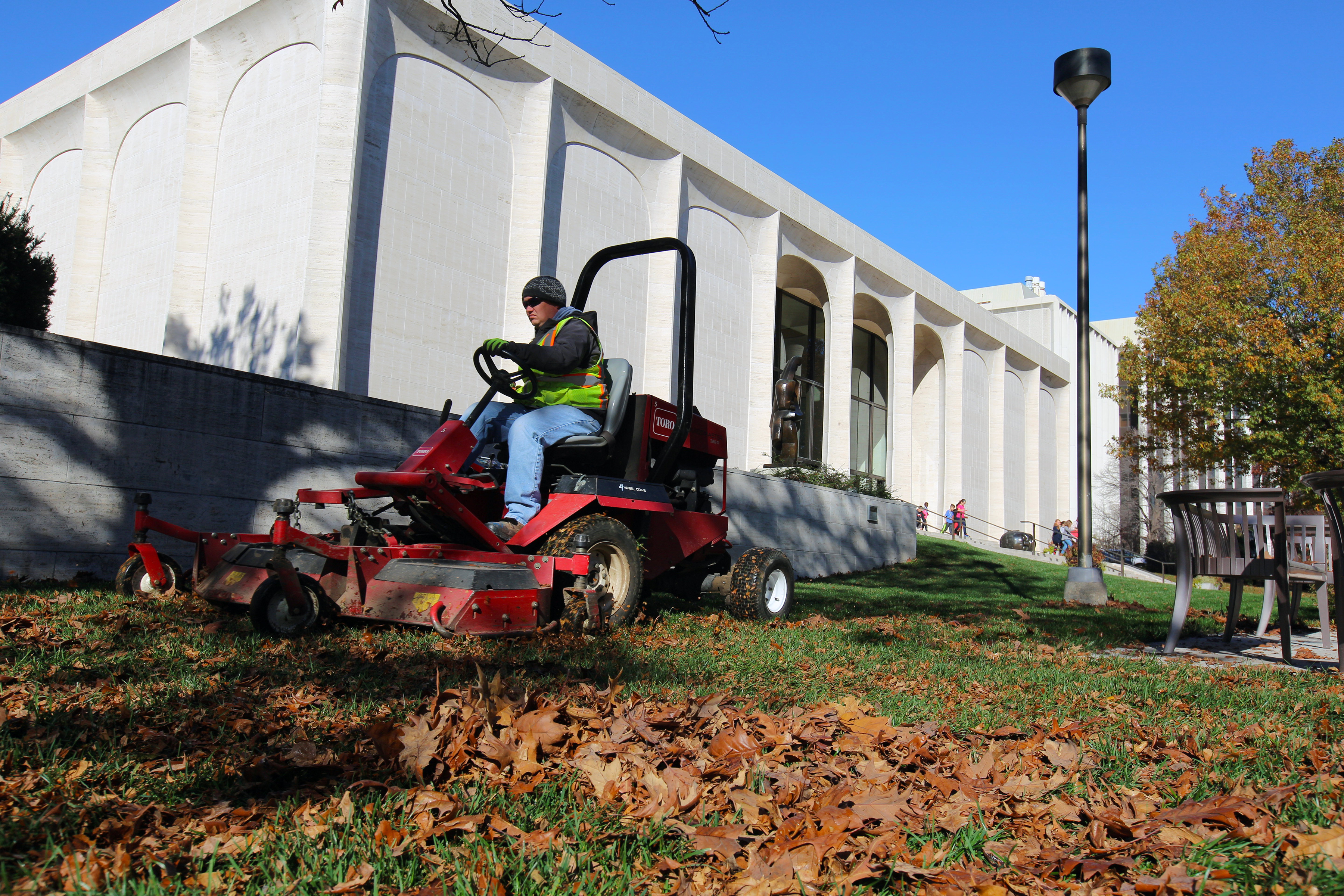 Tim Herron, a landscape assistant with landscape services, mulches leaves into the grass on the east side of Sheldon Museum of Art on Nov. 8. The university recently expanded its sustainability practices by partnering with Big Red Worms on leaf recycling.