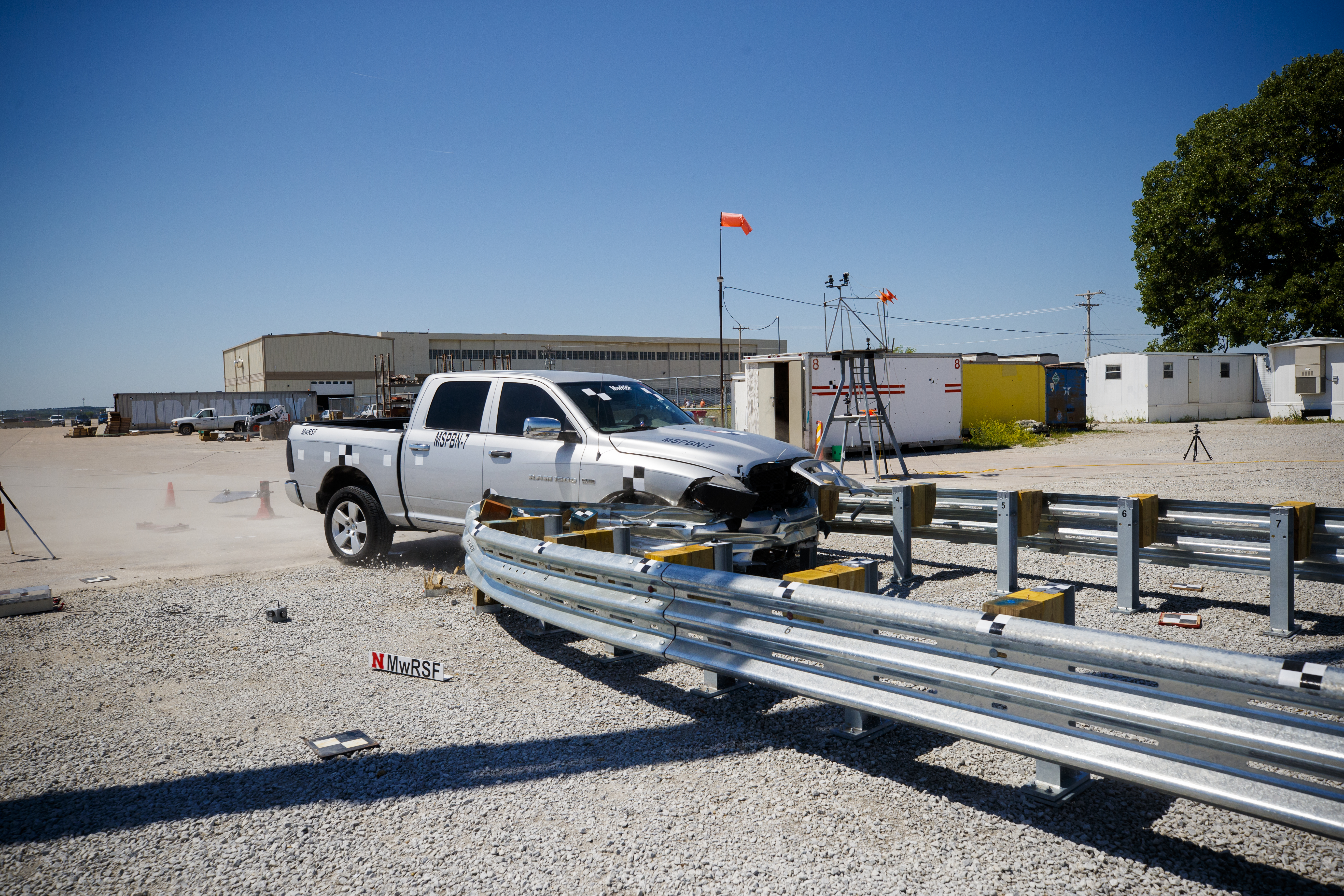 A truck crashes into a bull-nose barrier being tested for use in medians to protect cars from overpass columns. The front wood pylons are designed to shear off easily along with several metal ones. The shearing allows the energy of the crash to be transferred into the ground. Cables in the guard rails are designed to keep the car or truck captive and not let it deflect back into traffic.