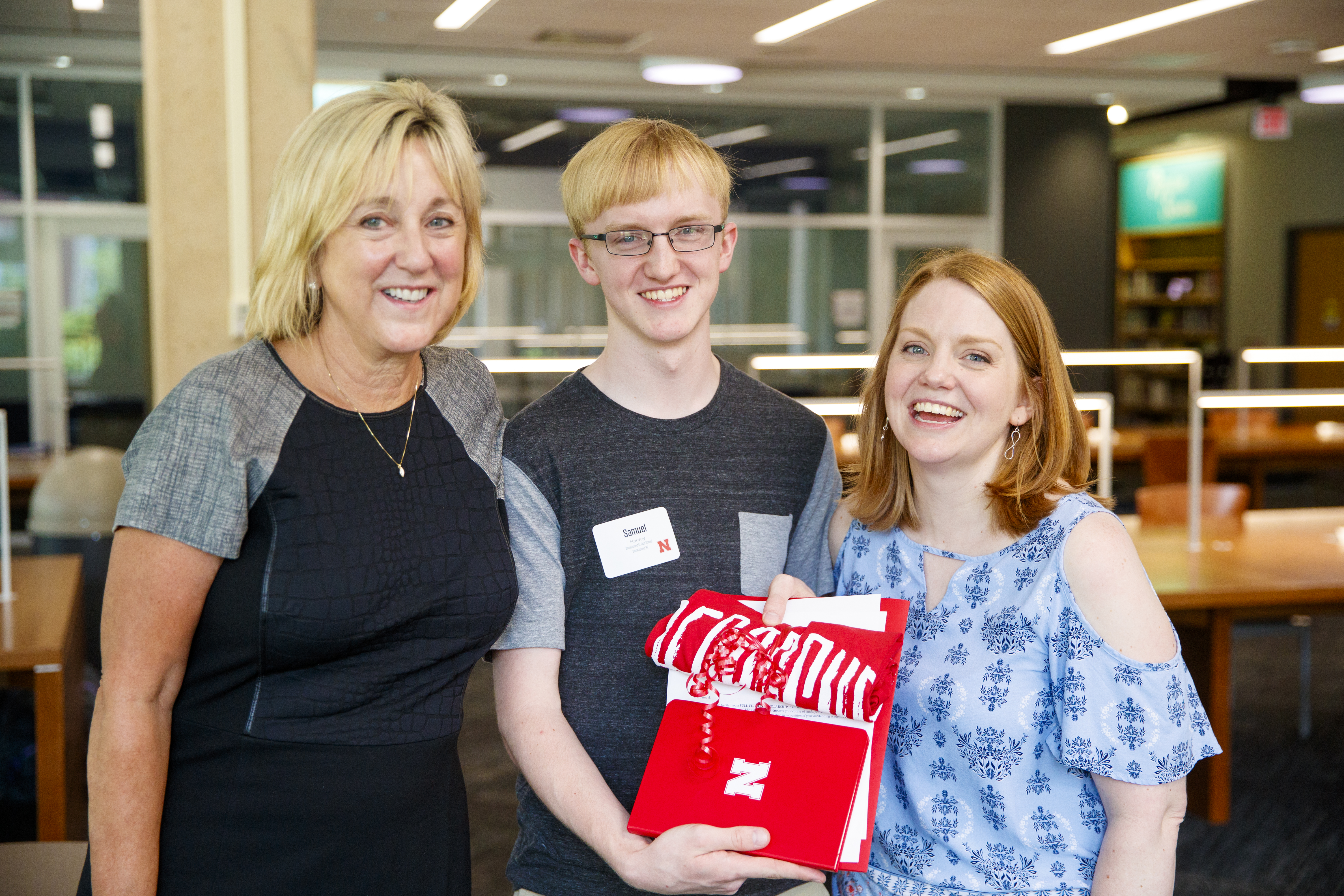 Donde Plowman, executive vice chancellor and chief academic officer, Samuel Harvey and his mother, Elisia Flaherty, after Plowman presented Harvey with admission to the university and a full-tuition scholarship