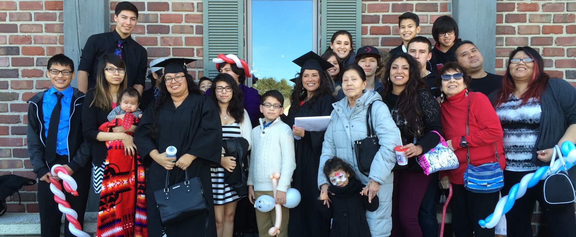 Two graduates of the Indigenous ROOTS Teacher Education Program gather with their families. A new grant will allow the program to expand its efforts and focus on training Indigenous school principals and administrators.