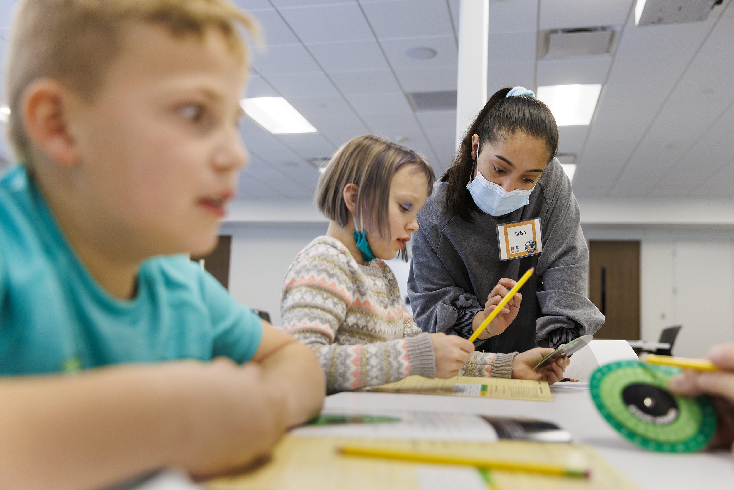 Honors student Brisa Rios helps 8-year-old Audrey with decoding using a cipher wheel.