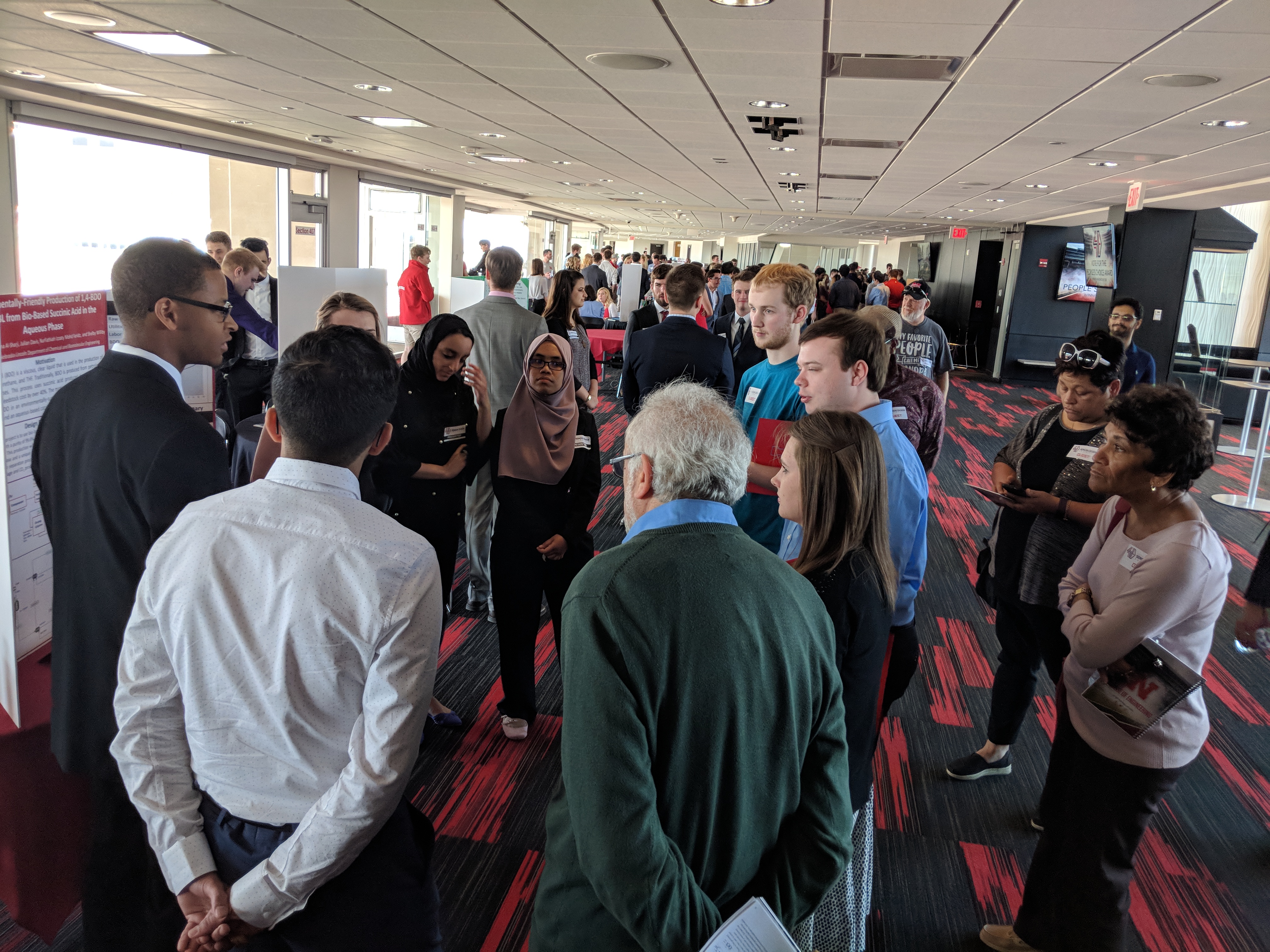 People standing around student booth at previous Senior Design Showcase