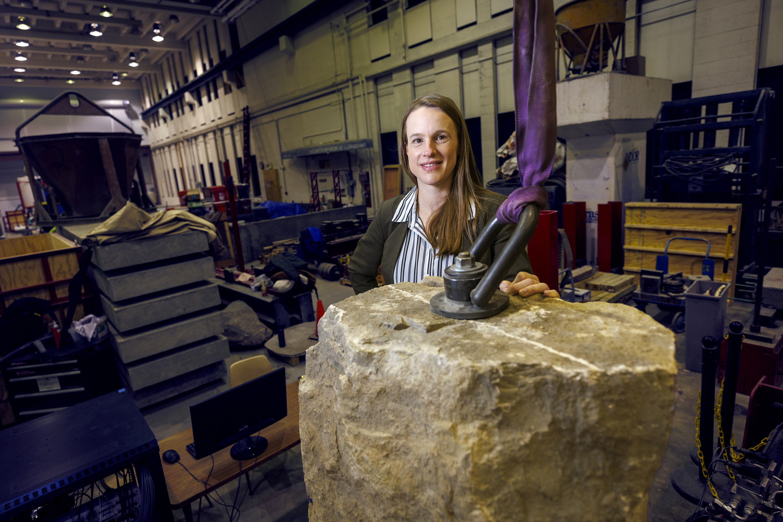 Christine Wittich standing behind giant rock in cluttered workshop