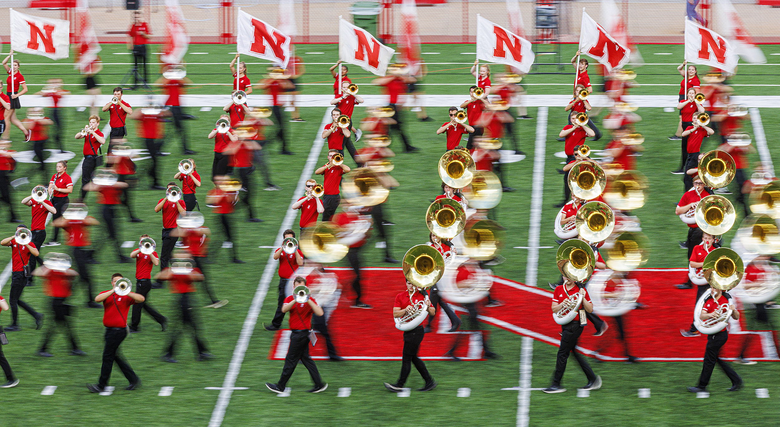 Lines of Cornhusker Marching Band members cross each other on the field at Memorial Stadium