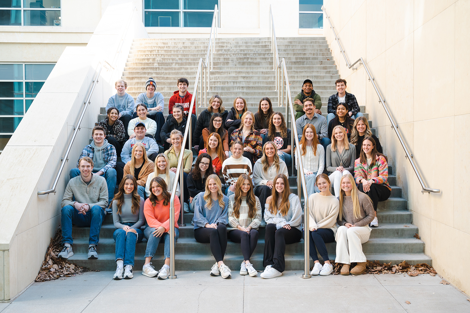 The new strengths coaches in the Clifton Strengths Institute sit on a staircase outside Howard L. Hawks Hall.