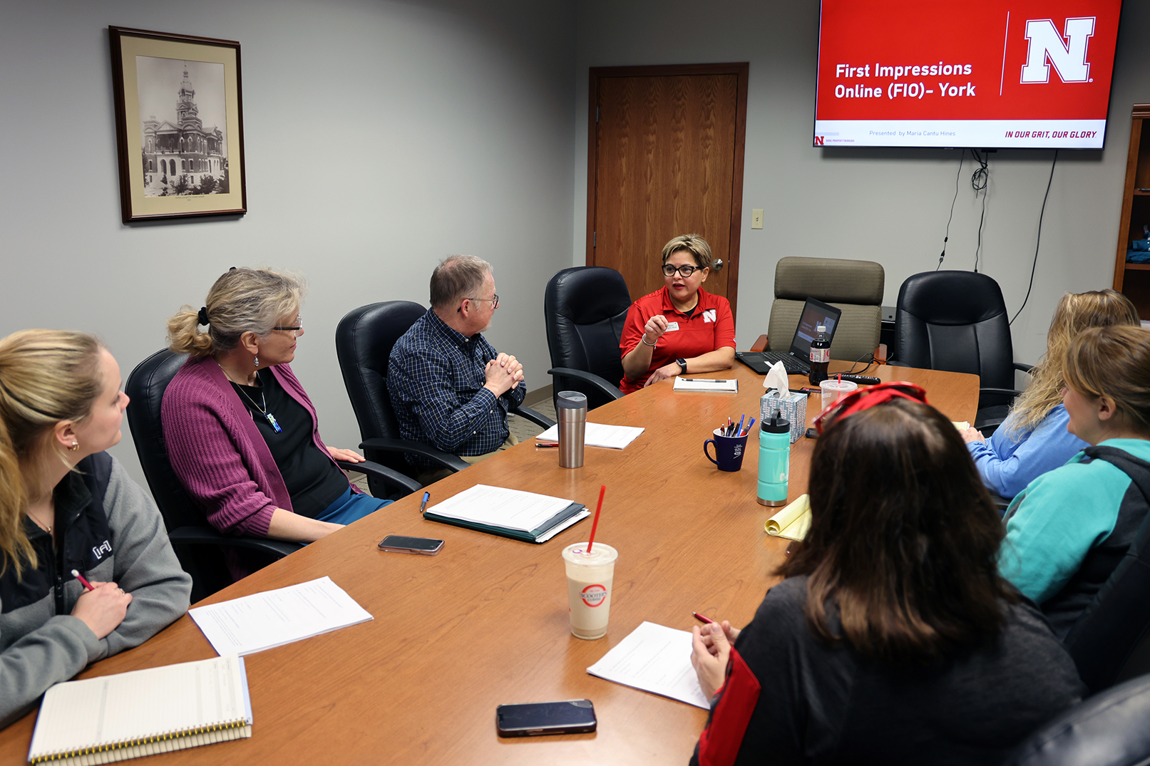 Seven people gather around a conference table.