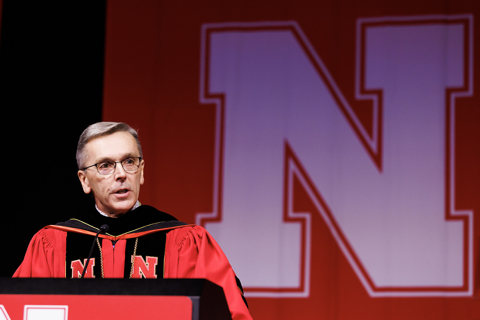 Chancellor Ronnie Green, dressed in his doctoral robe, stands behind the lectern at commencement.