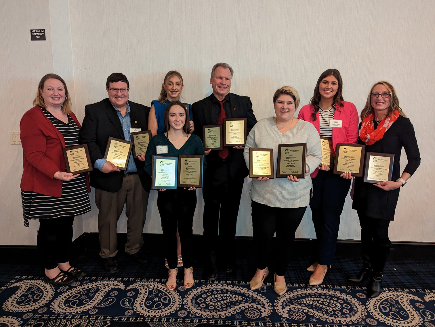 Two men and six women hold plaques.