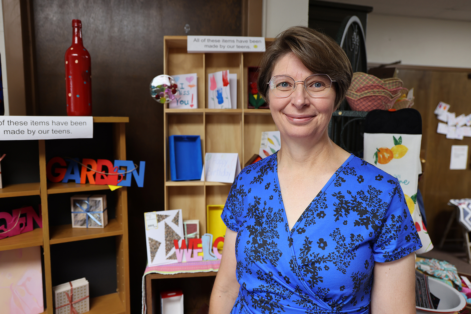 Adeline Johnson stands in front of crafts made by students at Our Place After School Care and sold at the Freedom Factory.