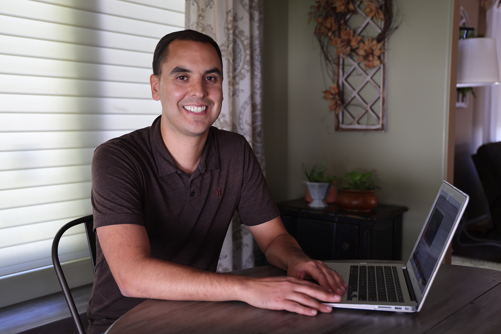 Jon Alvarado sits at a table with his laptop.