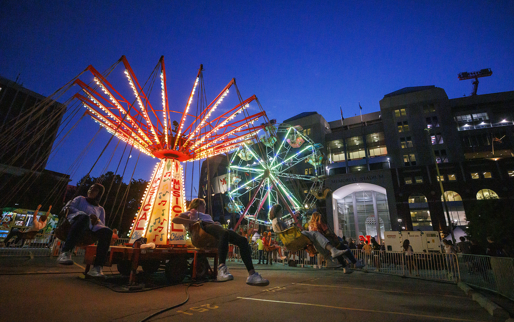 The Musical Chairs ride and Ferris wheel light up the East Stadium Plaza during the 2022 Cornstock Festival.