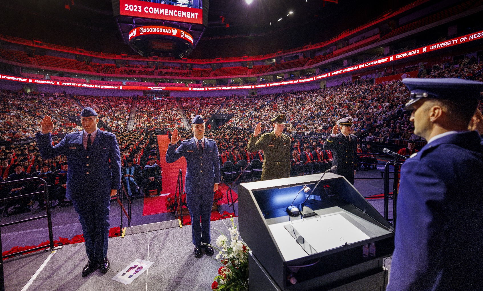 Four ROTC members recite the oath of enlistment on stage at undergraduate commencement.