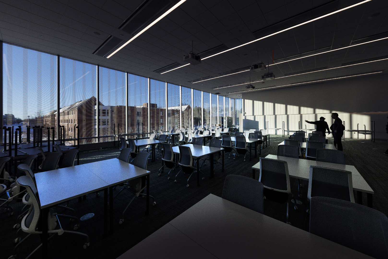 Two men stand amid the sunlight in a Kiewit Hall classroom.