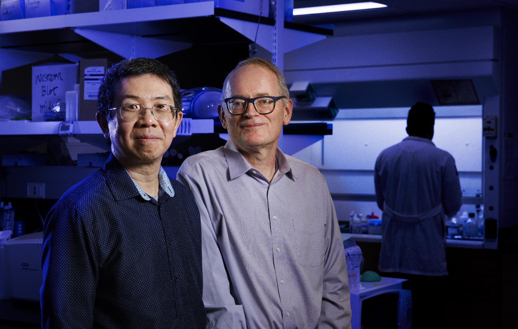 Jiantao Guo and Janos Zempleni stand next to each other in a blue-lit lab.