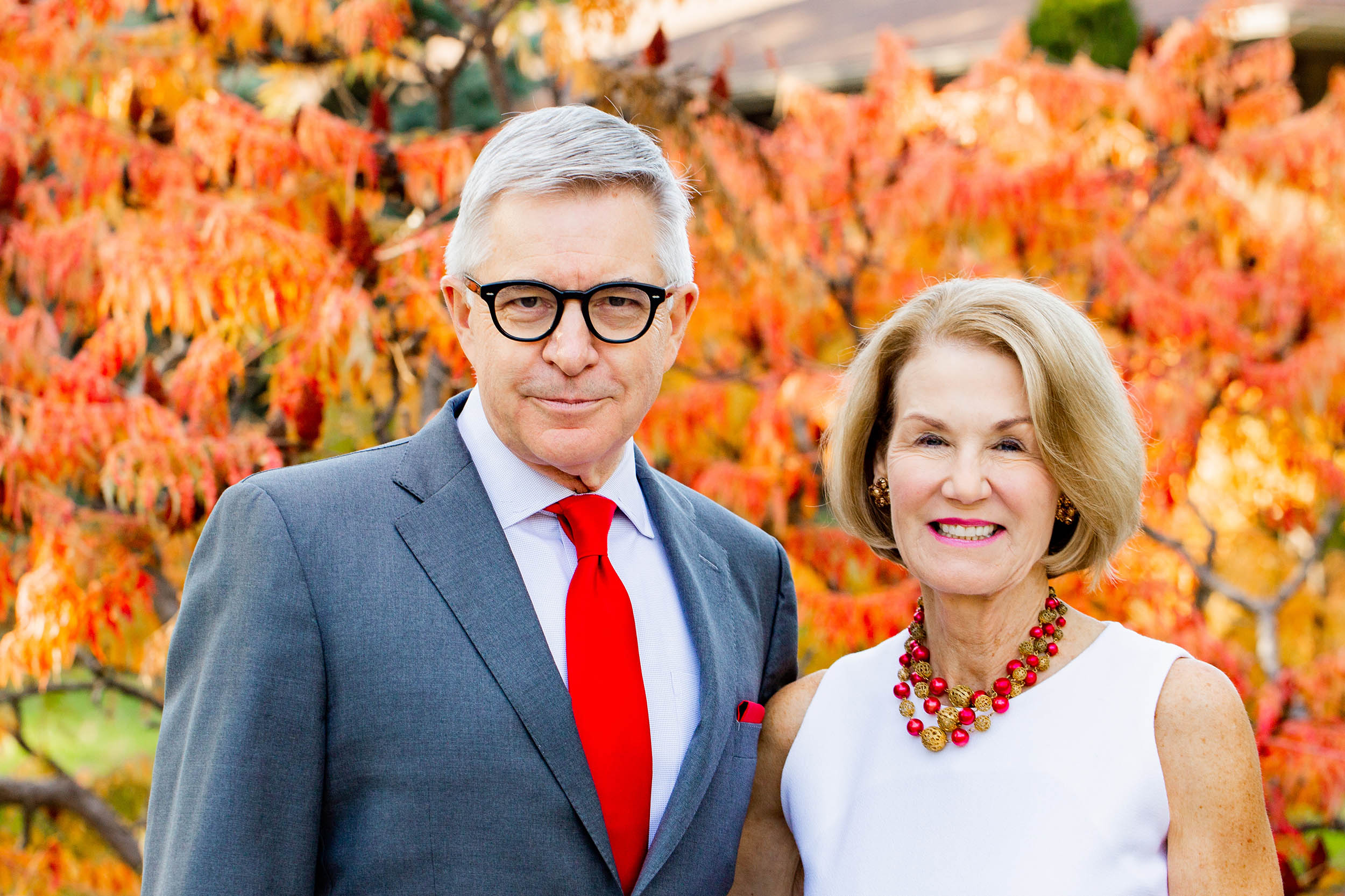 Tom and Candy Henning stand in front of autumn leaves.