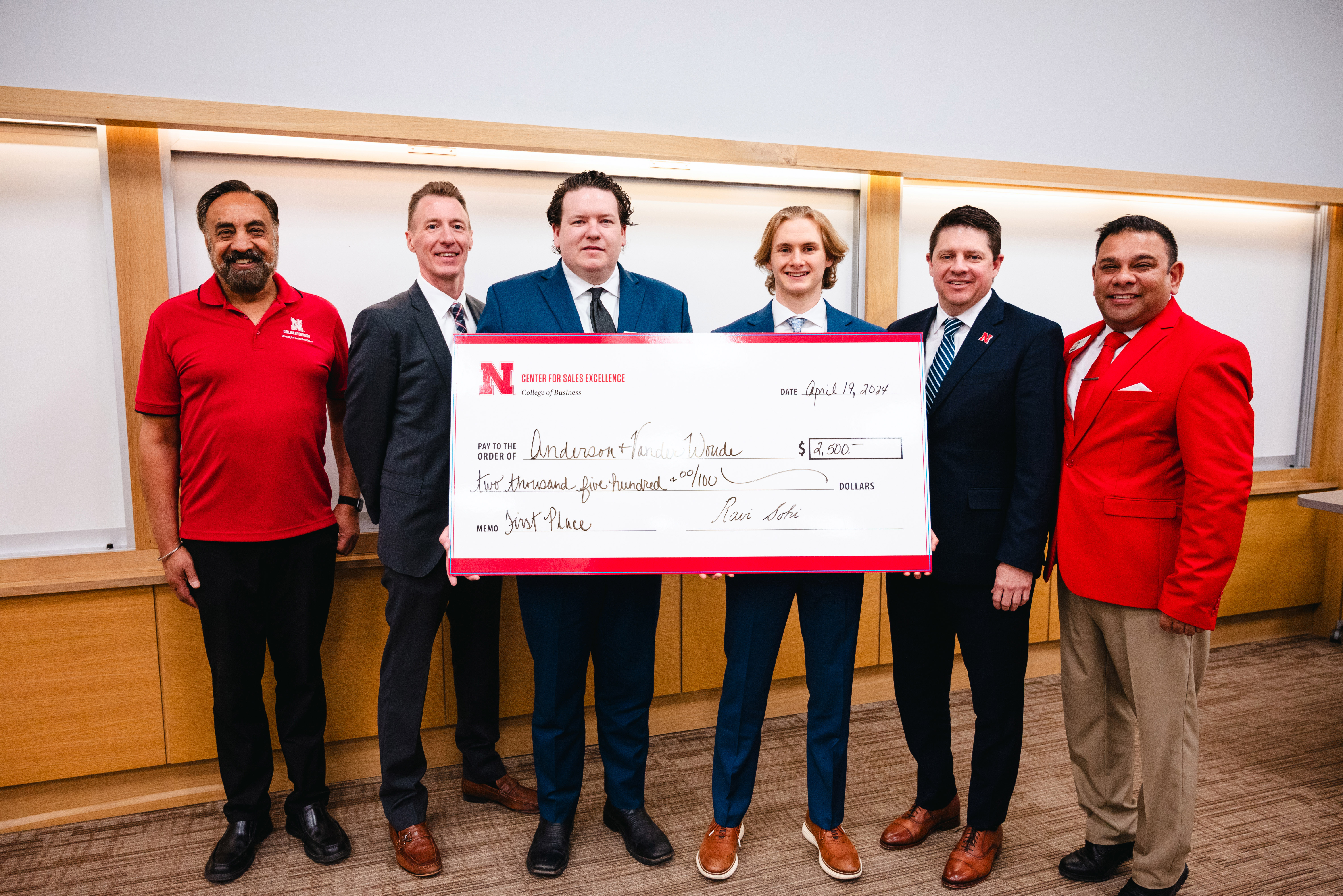 Six men pose with an oversized check.