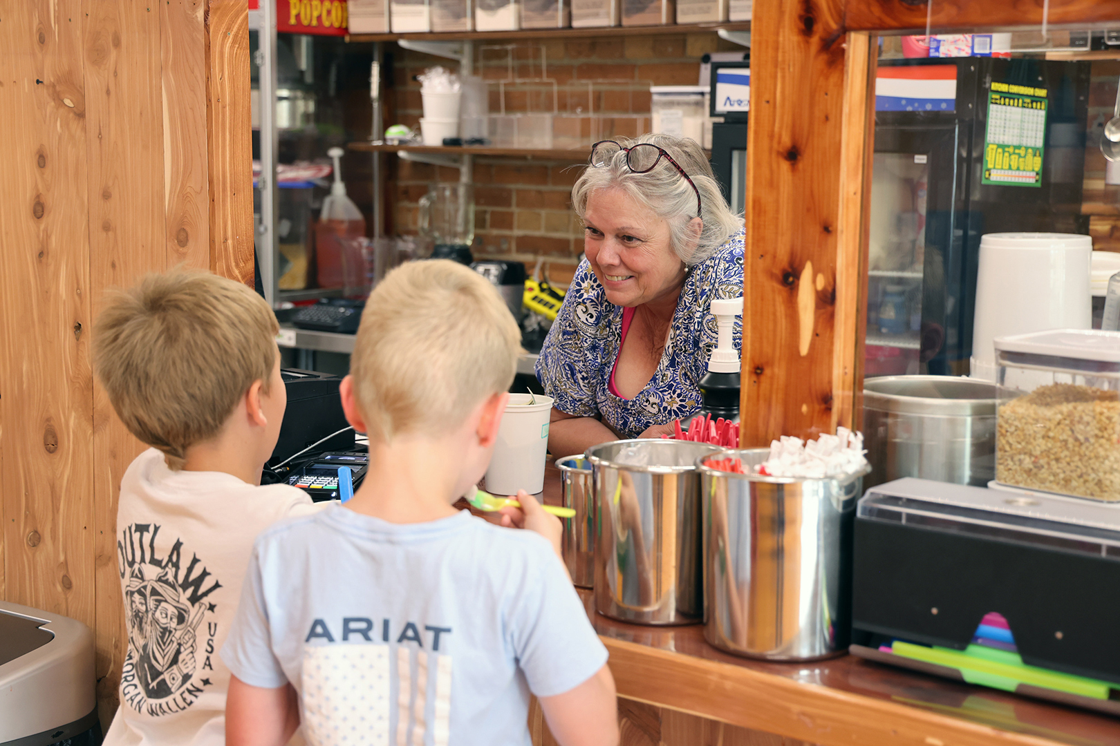 A woman serves ice cream to two boys.