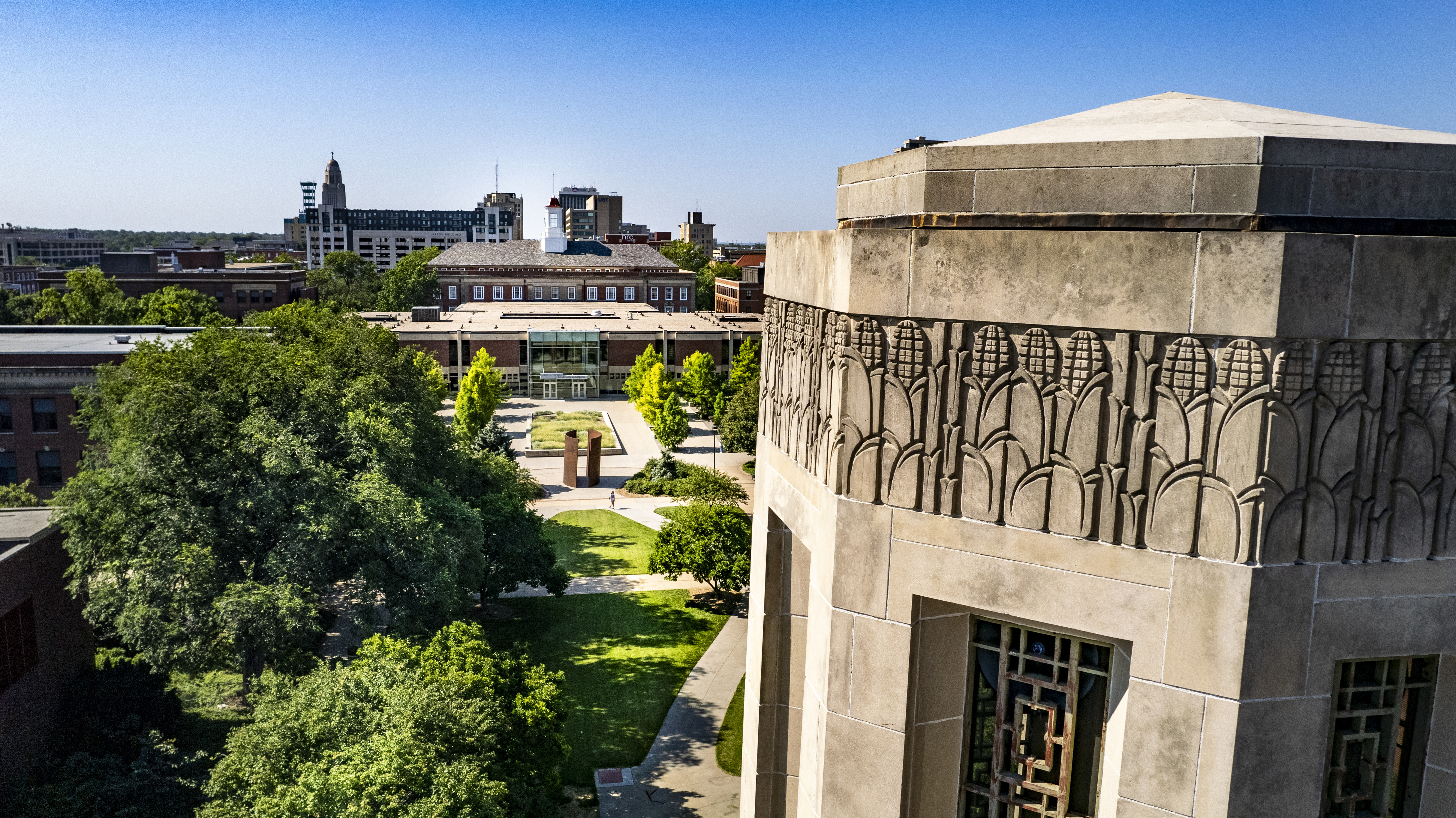 An aerial shot of the top of Mueller Tower, the "Greenpoint" sculpture and Love Library.