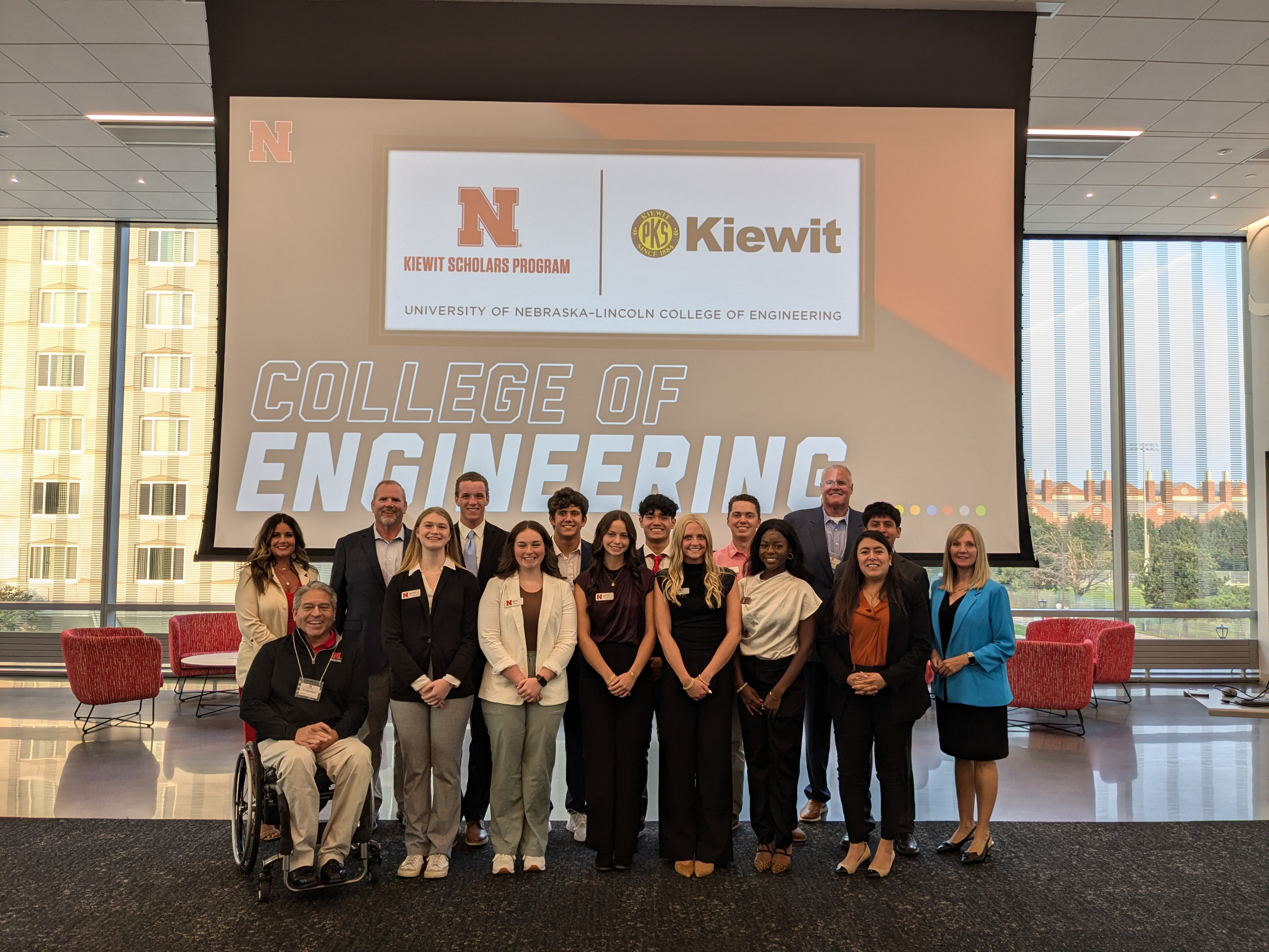 Ten Kiewit Scholars, College of Engineering Dean Lance C. Pérez and six Kiewit representatives pose for a photo in front of a screen that reads "College of Engineering."