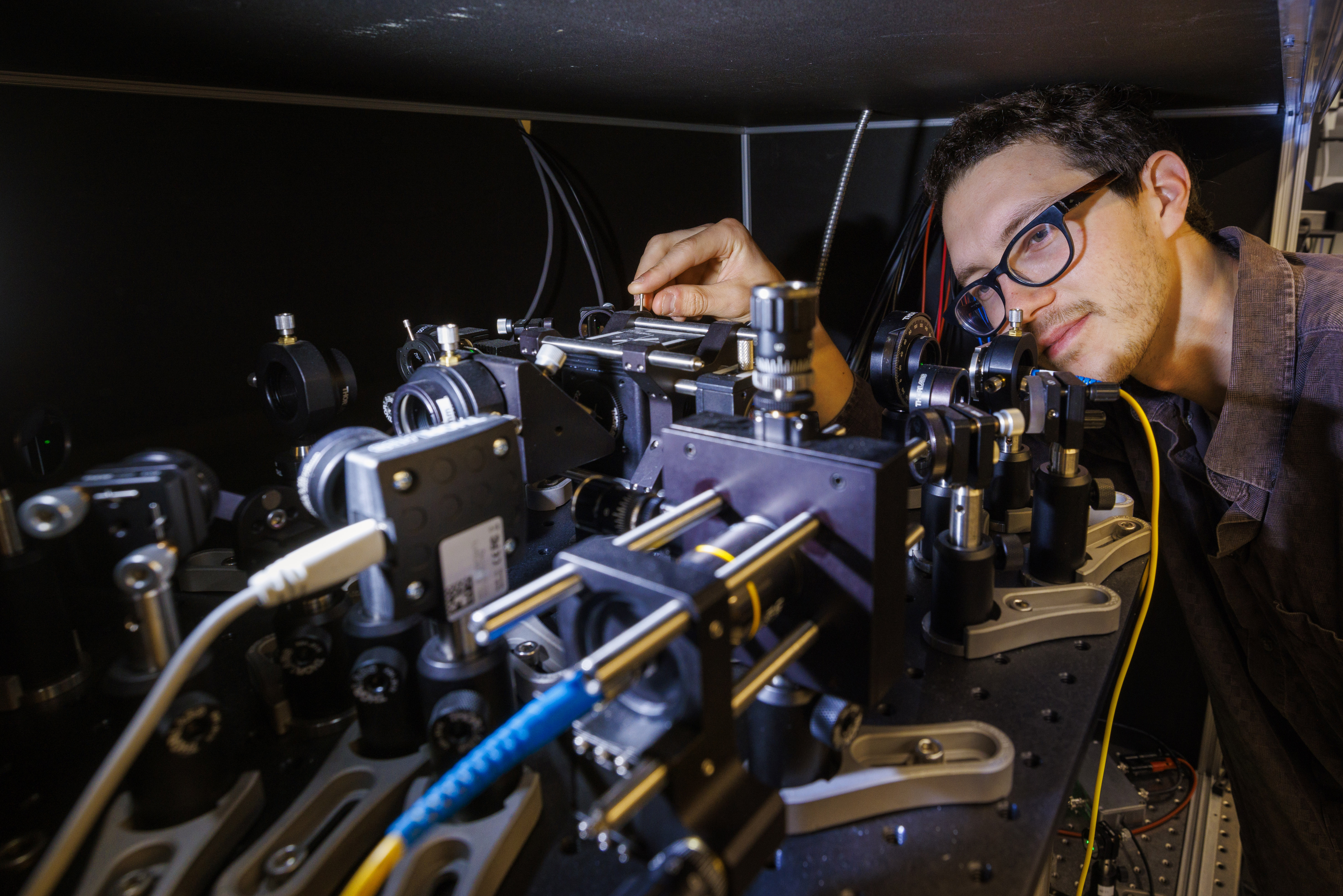 Adam Erickson adjusts a large, complex microscope.