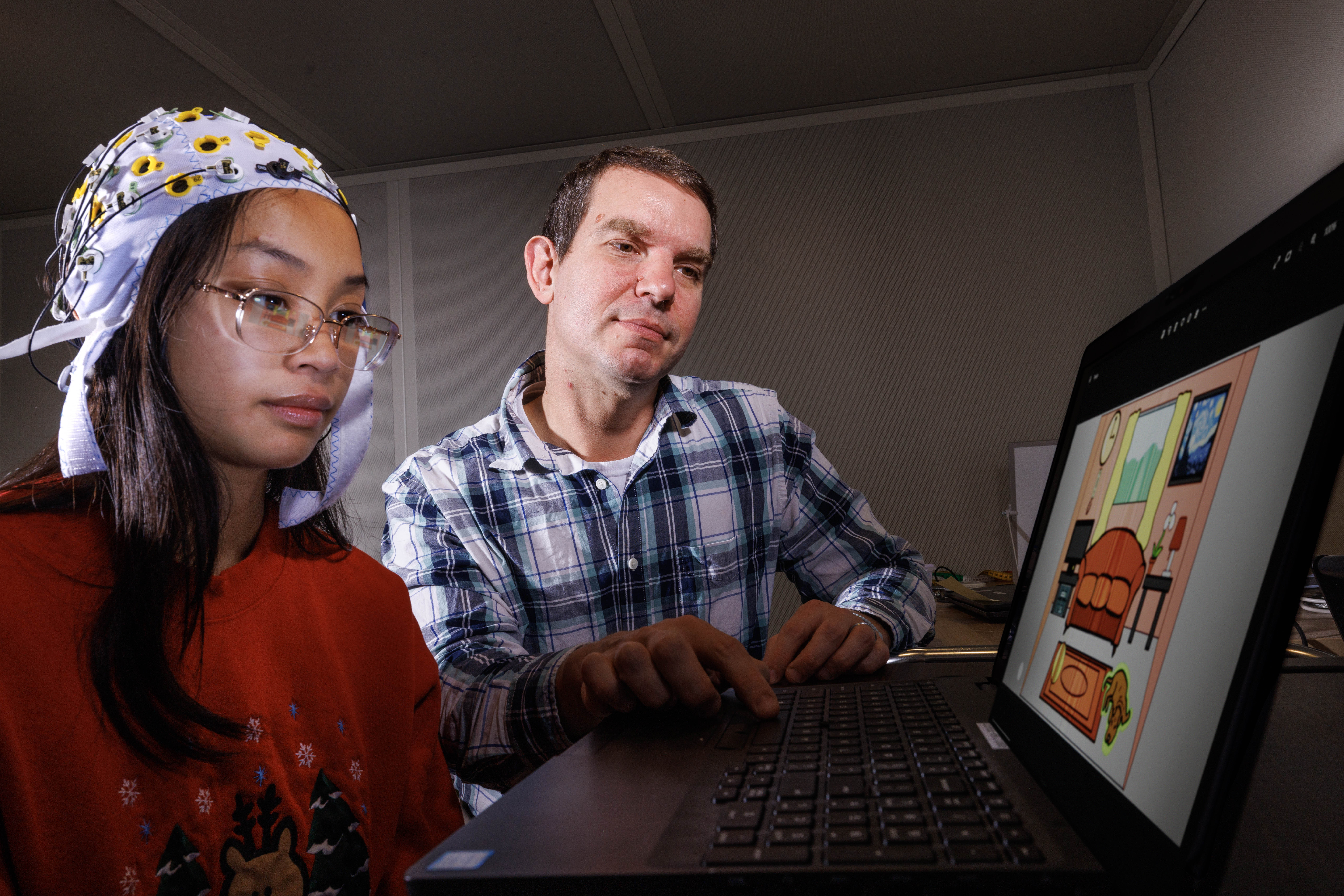 Cutline 1: Kevin Pitt, assistant professor of special education and communication disorders, demonstrates an electrode cap in the AAC Translation Lab with Aliyah Muniz, a senior speech-language pathology major.