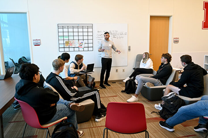 A young man leads a small group of students in a classroom.