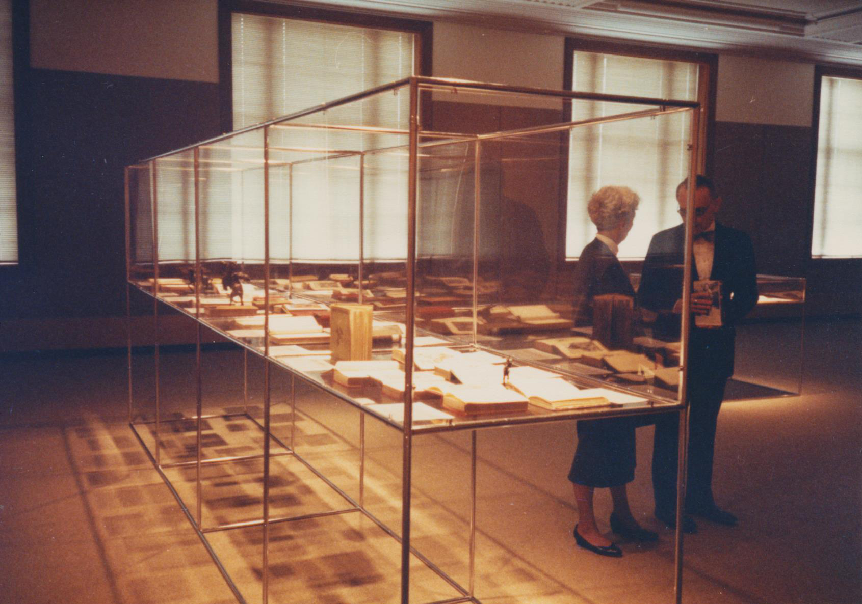 A man and woman stand next to a museum display case in Love Library.