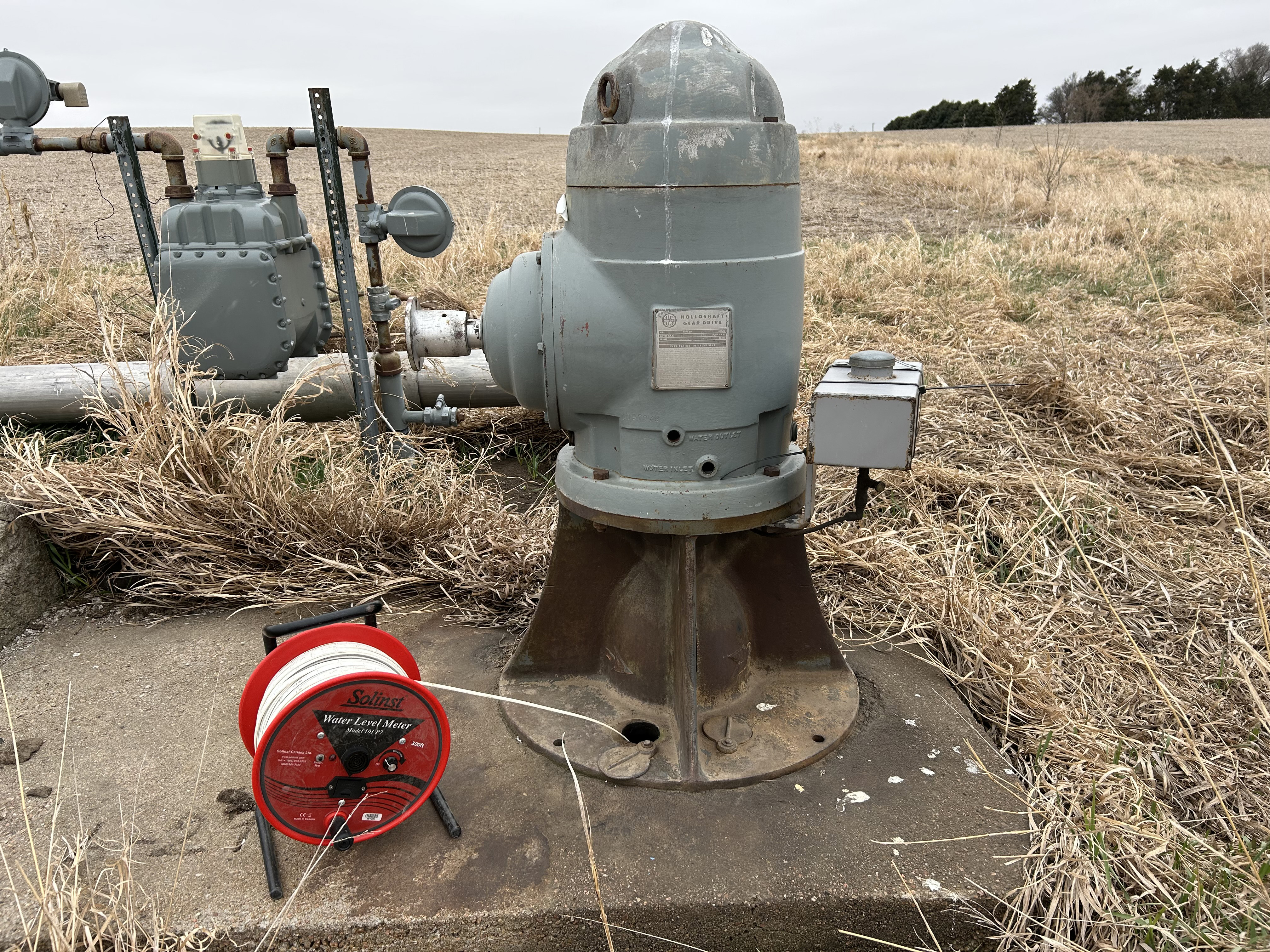 A well measuring tape is positioned next to an irrigation well head in preparation for making a water level measurement.