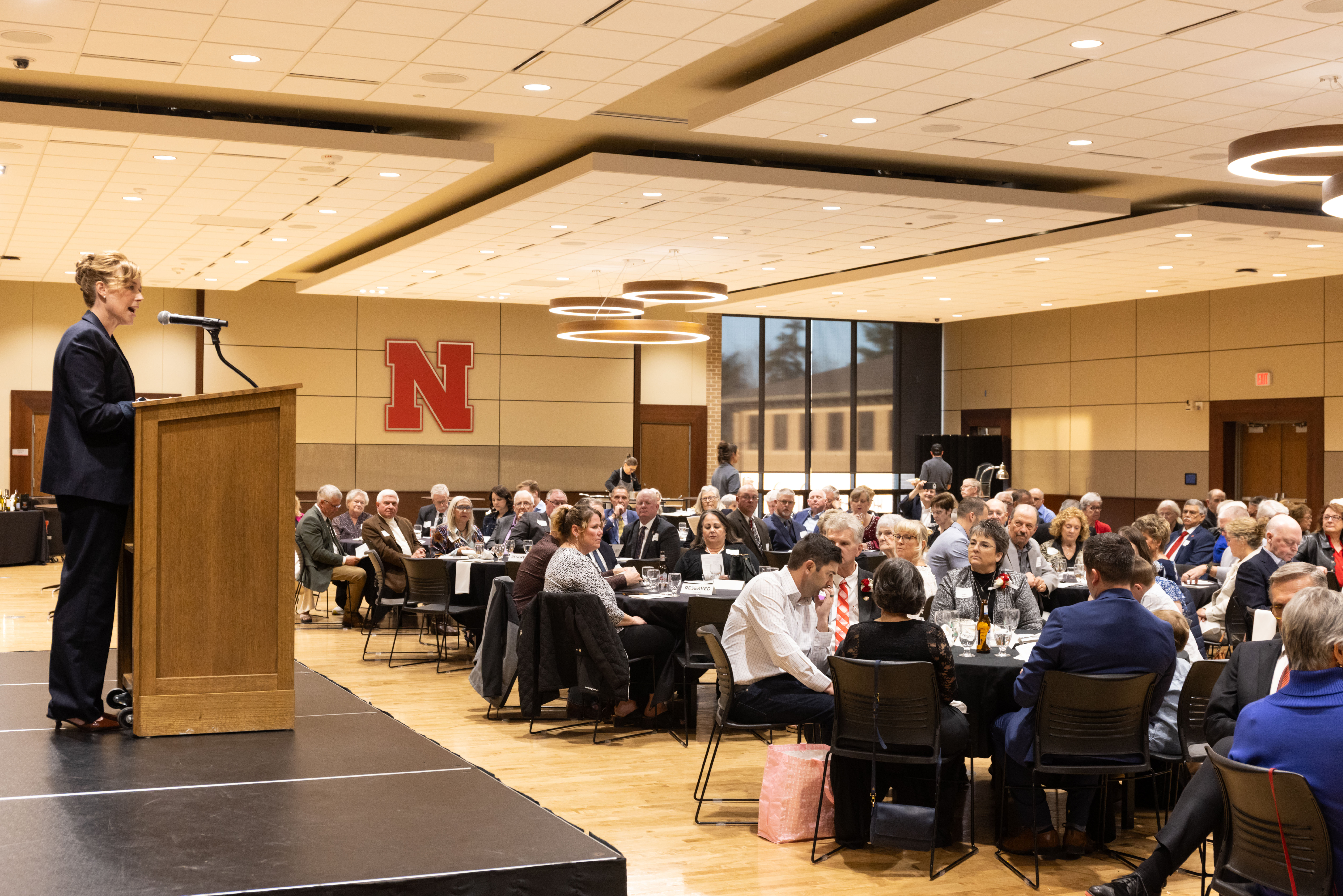 Tiffany Heng-Moss, Harlan Vice Chancellor for the Institute of Agriculture and Natural Resources at the University of Nebraska–Lincoln and vice president for agriculture and natural resources for the University of Nebraska system, speaks at a lectern in a crowded conference room in the Nebraska East Union.