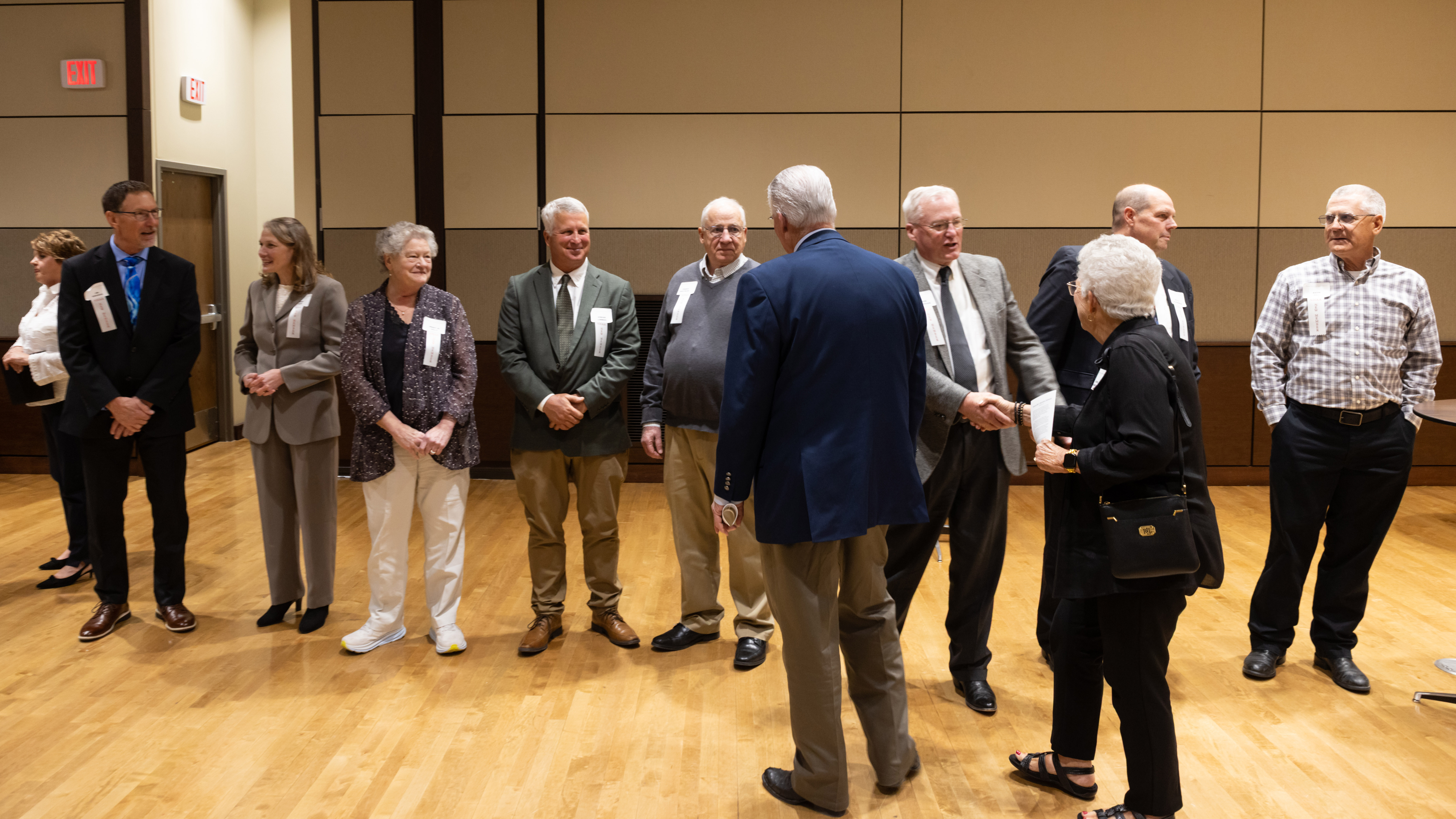 Six men and two women — all new inductees in the Nebraska Hall of Agricultural Achievement — stand in a handshake line in a conference room in the Nebraska East Union.