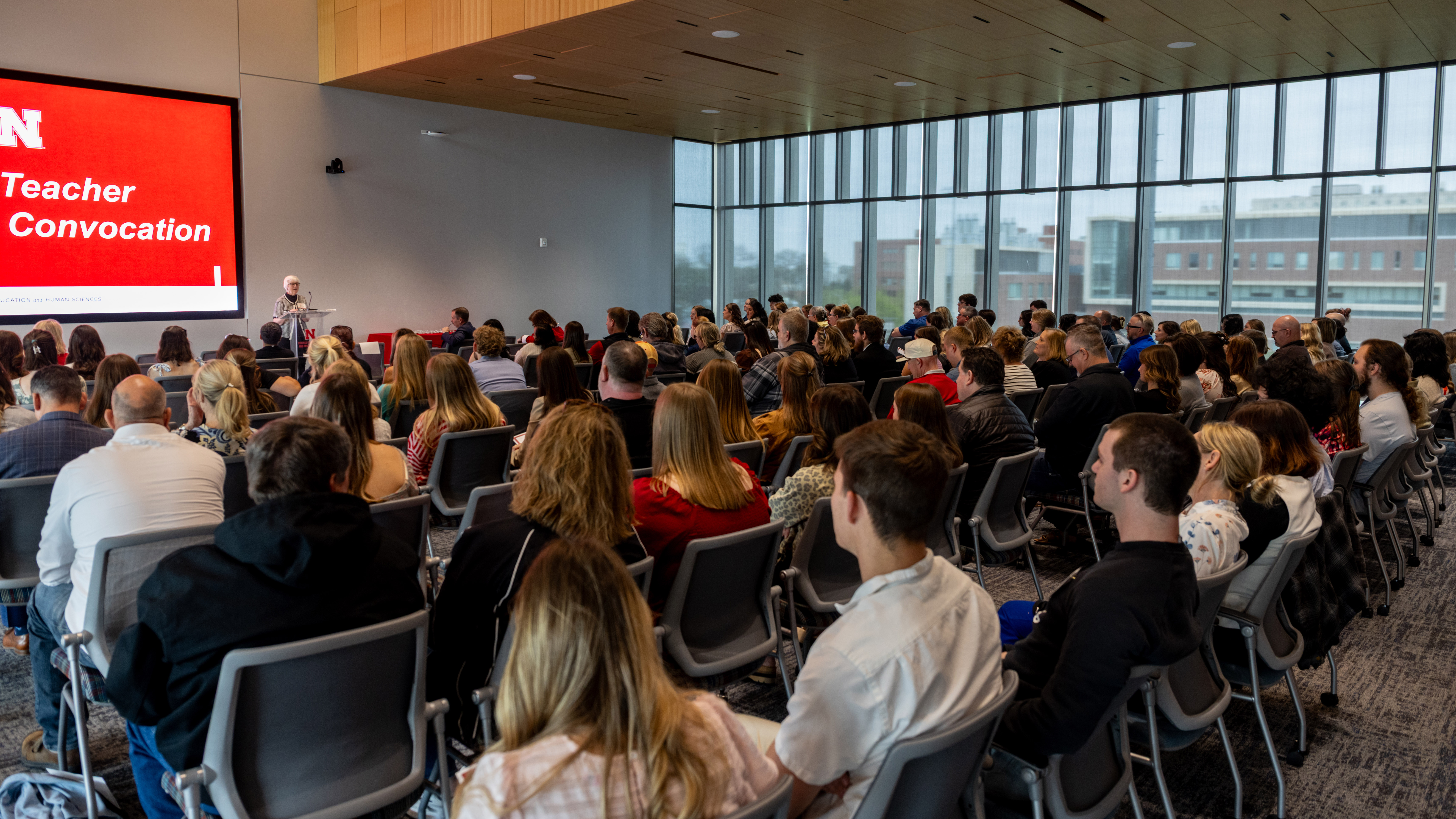 Marjorie Kostelnik, emeritus dean of the College of Education and Human Sciences, speaks at a lectern to a large, seated crowd.