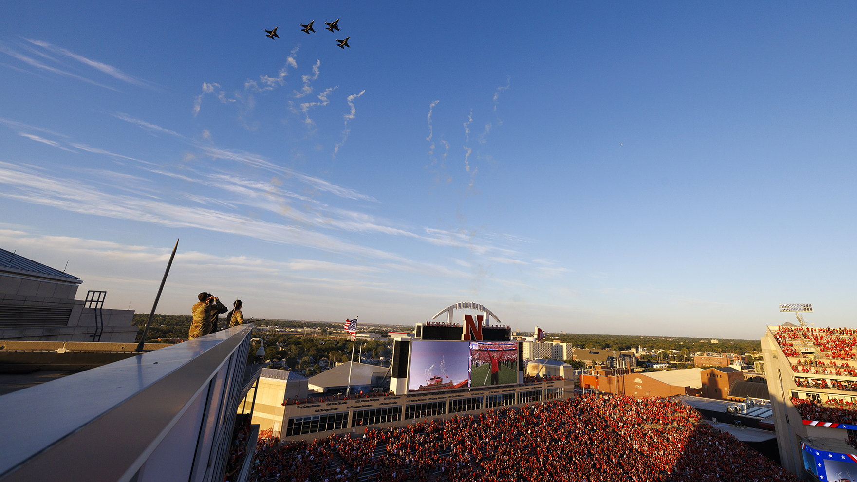 ROTC Cadets Elena Burgwald and Mason Beck watch as four F-16s fly over Memorial Stadium Sept. 20.