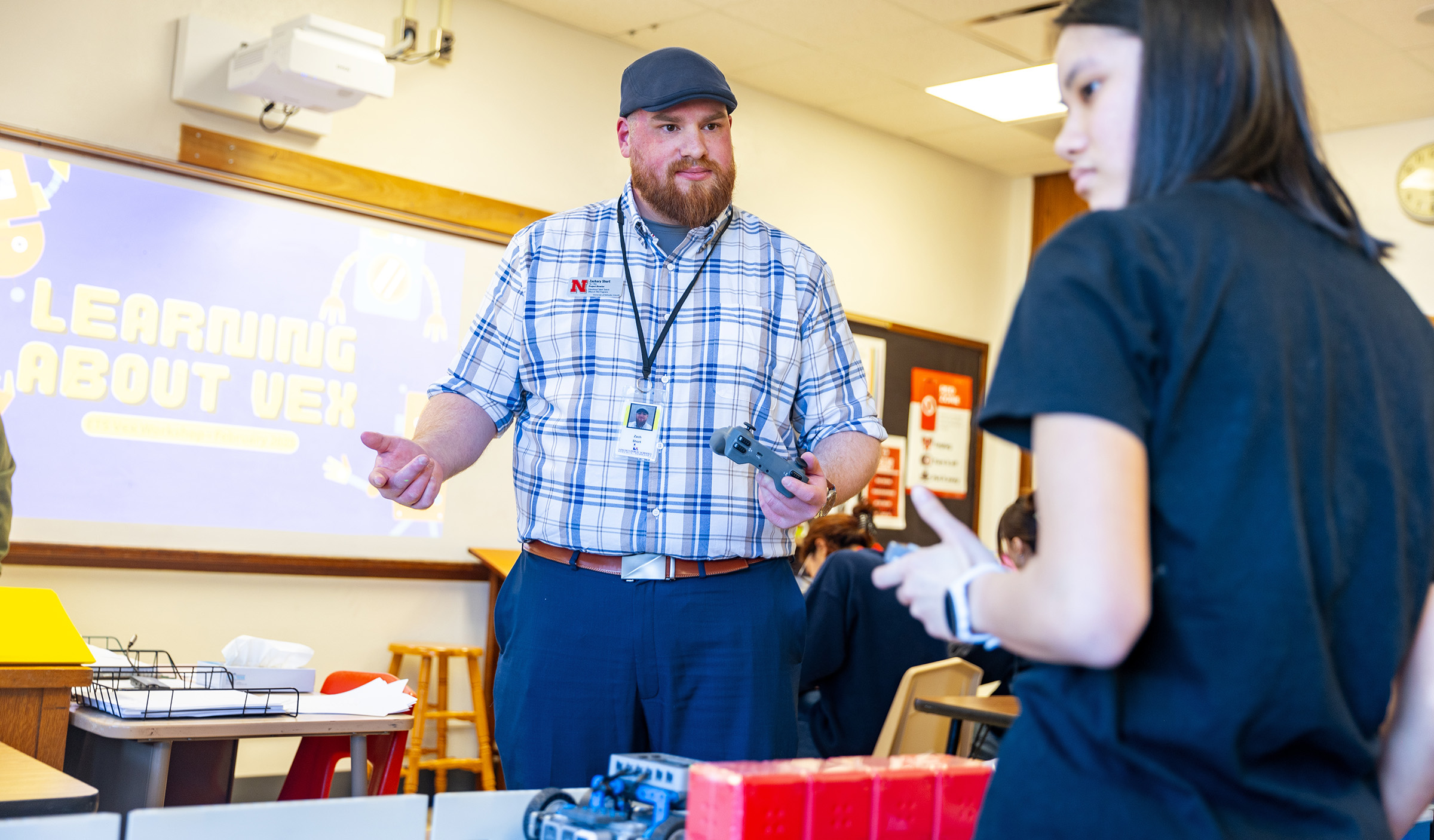 Zach Short, project director for Educational Talent Search, guides Lily Tran, a sophomore, through using the controls to make the robot move.