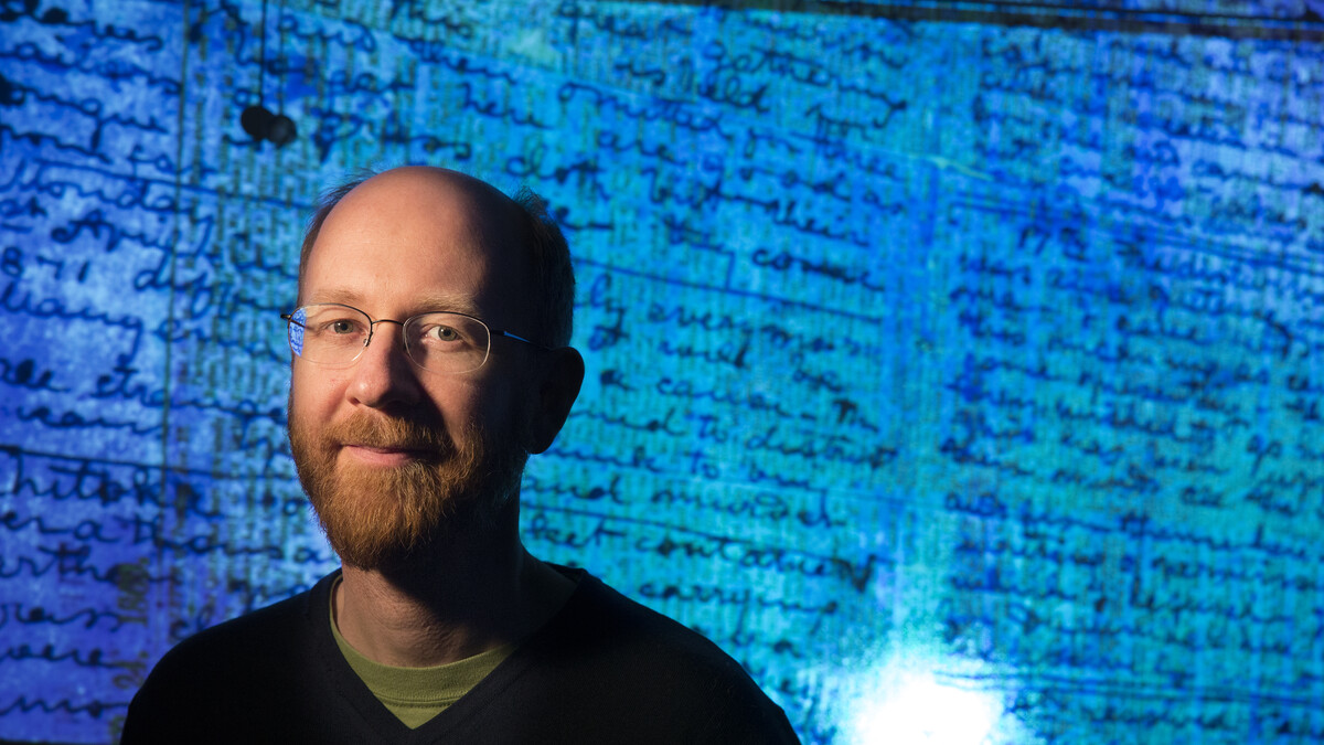 drian S. Wisnicki, assistant professor of English,  stands in front of a projected image of Dr. David Livingstone's  1871 diaries made readable using spectral imaging technology.