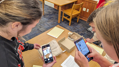 Students take photos of a medieval manuscript.