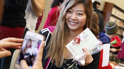 Caitlin Dinh displays her chocolates and Valentine's Day gifts Feb. 14 as her friend takes her photo in the Kawasaki Reading Room.  