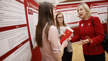 Donde Plowman, executive vice chancellor and chief academic officer, discusses a research project with students during the 2017 Spring Research Fair.