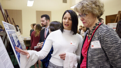 Sen. Sue Crawford (right) listens as Husker Jayden Barth explains the effects of prior education on the success of inmates in prison education programs. Barth was among the Nebraska undergraduates who presented to state senators during the 2018 Spring Research Fair.