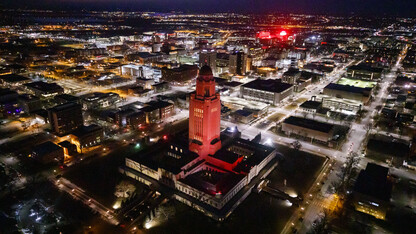 The Nebraska State Capitol shines red with Memorial Stadium and City Campus in the background.
