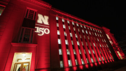 The architecture of Nebraska's Love Library is highlighted by red light and the N150 logo for Glow Big Red.