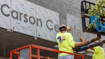 Contractors from Patriot Steel Erection install signage on the exterior of the new Carson Center for Emerging Media Arts on Aug. 5. The program launches with the start of the fall semester. 
