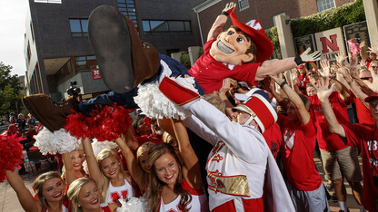 Herbie Husker crowd surfs with some help from the Cornhusker Marching Band, cheerleaders and Nebraska alumni outside the Wick Alumni Center.