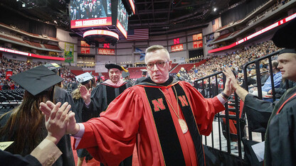 Chancellor Ronnie Green and Kevin Hanrahan, associate professor of voice and vocal pedagogy and Faculty Senate president, give high-fives to graduates as they walk onto the Pinnacle Bank Arena floor Dec. 15.