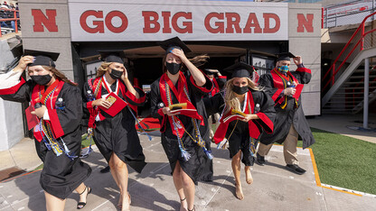 Graduates hang on to their mortar boards and stoles as they walk onto the field at Memorial Stadium for the morning undergraduate ceremony May 8.