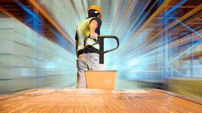 Man in hard hat pulling cart full of boxes