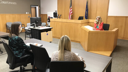 Michelle Paxton, director of the Children's Justice Clinic, talks with two student attorneys in the Judge Donald R. and Janice C. Ross Courtroom in the College of Law. Clinic student attorneys practice with Paxton before going to court.