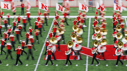 Lines of Cornhusker Marching Band members cross each other on the field at Memorial Stadium