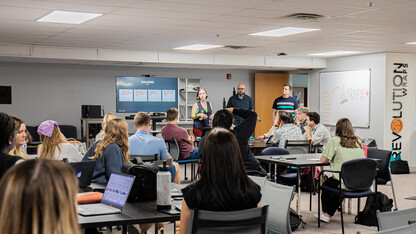 Three representatives of Swanson Russell — two men and a woman — speak to a room of a dozen-plus students in the Jacht Ad Agency.