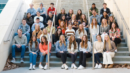 The new strengths coaches in the Clifton Strengths Institute sit on a staircase outside Howard L. Hawks Hall.